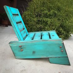 a blue wooden chair sitting in front of a bush