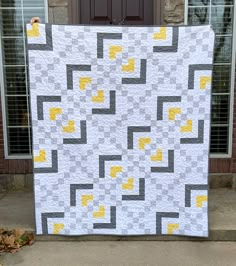 a large white and yellow quilt sitting on top of a cement floor next to a door