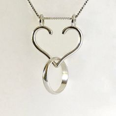 "Ring Necklace Holder, also called an Engagement Ring Holder or Wedding Ring Holder, is a great way to wear your rings when you can't have them on your hands. A Ring Holder Necklace is also a meaningful way to wear the rings of someone dear to you. To see more of my Ring Holder Necklace Designs, here is their section: https://www.etsy.com/shop/AliCArt?ref=l2-shopheader-name&section_id=19372510 To put your rings on the holder, slide the chain off one top loop, put your ring through the openin Minimalist Wedding Jewelry With Heart Charm, Minimalist Jewelry For Valentine's Day Promise, Symbolic Sterling Silver Promise Jewelry, Minimalist Heart Pendant Jewelry For Wedding, Unique Heart Pendant Jewelry For Wedding, Sterling Silver Promise Jewelry, Unique Heart Pendant Wedding Jewelry, Symbolic Promise Jewelry For Valentine's Day, Unique Wedding Jewelry With Heart Pendant