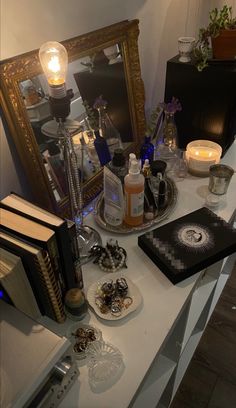 an assortment of items on a table in front of a mirror and light bulb lamp