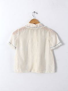 This is a silk blouse circa 1920s. The cream silk top features pin tuck pleats down the front with blue laced stitching and lace trim. It buttons closed. CONDITIONIn good condition with wear consistent with age and use. Approximate Fit: XSMEASUREMENTSBust: 30" ... 76. 2 cmLength: 18" ... 45. 7 cmShoulders: 12" .. 30. 5 cmOutside Sleeve: 8" ... 20. 3 cm HOW WE MEASURE• Blouse measured lying flat• Bust measured armpit to armpit• Length measured down the center of the back• Shoulders measured between the shoulder seams• Outside Sleeve measured from the shoulder seam to end of sleeve on outside of arm. 21702 Short Sleeve Tops With Pintucks For Daywear, Silk Tops With Lace Trim For Daywear, Vintage Lace Collar Button-up Top, Vintage Silk Short Sleeve Blouse, Vintage Silk Blouse With Short Sleeves, Silk Ruffled Short Sleeve Top, Silk Ruffle Short Sleeve Top, Cream Top With Ruffled Collar For Daywear, Silk Collared Top For Daywear