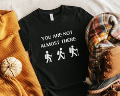 This funny hiking shirt makes a great addition to your wardrobe! Pair with other nature clothing to stand out from the crowd and embrace your sarcastic side. This also makes a great gift for anyone who loves camping, backpacking, hiking, and all things outdoors! You are not almost there t shirt.  ✳ Made to Order ✳ Pre-Shrunk ✳ Various Colors and Unisex Sizes ✳ Slim Fit ✳ Soft, High-Quality Fabric ✳ Please note: there may be a slight color variation due to lighting and different screen settings ✳ If you need a different color or size, please reach out and I'll see what I can do for you!  Sizing ✳ Please check the listing photos for sizing to ensure you understand the length and width ✳ If you are unsure, measure a comparable piece from your wardrobe Care Instructions ✳ Cold Wash ✳ Tumble dr Funny Hiking Shirts, Funny Letter Print T-shirt For Outdoor, Fall Graphic Print T-shirt For Outdoor Activities, Graphic Print T-shirt For Outdoor Activities In Fall, Fall Hiking T-shirt With Graphic Print, Black T-shirt For Hiking With Letter Print, Black Hiking T-shirt With Letter Print, Black Letter Print T-shirt For Hiking, Black Crew Neck Shirt For Outdoor Activities