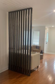 a living room with hard wood floors and white walls, along with a black radiator