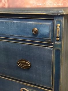 a blue dresser with brass handles and knobs