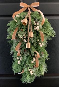 a christmas wreath hanging on the front door with bells and pine cones tied to it