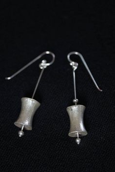 These earrings are composed of small silver beads and a bobbin-shaped hollow handmade silver piece, a design typical of Karen hill tribe people from northern Thailand. It is modernized into this simple composition, with the bobbin piece attached to a slender silver stem. It is crafted in 98% Silver, while the hook is in sterling silver. Our products are hand crafted in 98% Silver by Thai Karen hill-tribe artisans by means of traditional tools and techniques. The Karen are a group of ethnic peopl Handmade Modern Silver Plug Earrings, Modern Handmade Silver Plug Earrings, Handmade Minimalist Silver Plug Earrings, Minimalist Handmade Silver Plug Earrings, Silver Linear Earrings With French Hook Gift, Modern Silver Earrings With French Hook, Sterling Silver French Hook Drop Earrings, Silver Minimalist Dangle Plug Earrings, Silver French Hook Earrings As Gift