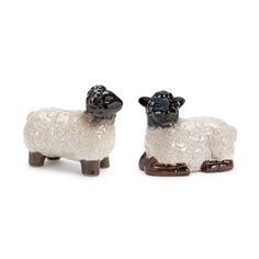 two black and white sheep figurines sitting side by side on a white background