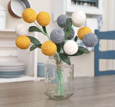 a vase filled with crocheted flowers on top of a wooden table