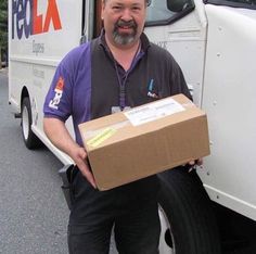 a man standing next to a delivery truck holding a box