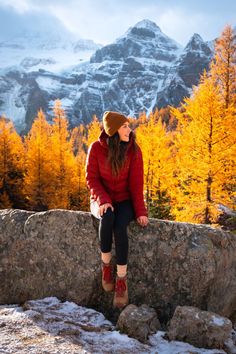 a woman sitting on top of a large rock