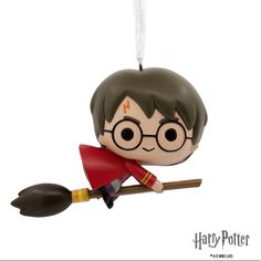 a harry potter ornament hanging from a string on a white background with a broom