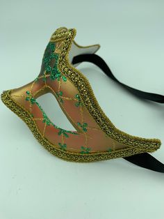 "This is a very nice original handmade and hand painted Venezia masquerade face mask made in Italy. The design on the shiny gold and orange face mask features turquoise blue and multi-color glitter with a border of gold lace and gold rope around the edges. It comes with a black ribbon tie and is stamped on the back \"Original Hand Painted Made in Italy Venezia\". The mask measures approximately 6 5/8\" long and 3 3/4\" wide and is in very good preowned condition with light wear on the back of th Green Carnival Masks And Prosthetics, Green Masks For Carnival Costume Party, Halloween Eye Mask As A Gift, Halloween Eye Mask Gift, Green Masquerade Mask For Mardi Gras, Green Mask For Masquerade Carnival, Green Masks For Masquerade Carnival, Green Masquerade Mask For Mardi Gras Party, Green Masks For Carnival Masquerade