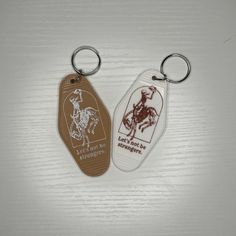 two keychains with the words, don't let the cowboys out on them