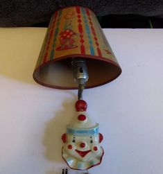 a lamp that is sitting on top of a table next to a white wall with a red and blue shade