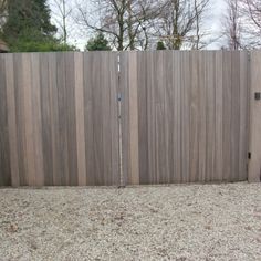 a wooden fence in front of a house with gravel on the ground next to it