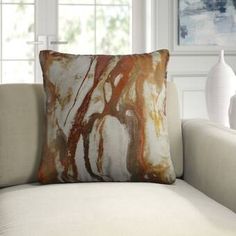 a white couch with a brown and orange pillow sitting on it's back end