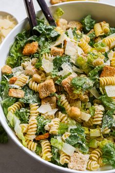 a white bowl filled with pasta salad and two black chopsticks in the side