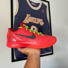 a person holding up a red shoe in front of a basketball jersey