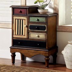 a wooden cabinet with several drawers in front of a window and a vase next to it