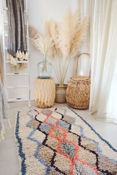 a white rug with blue, orange and red designs on it next to a basket