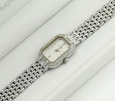 This silver-colored watch boasts a rectangular case surrounded by stones, adding a touch of elegance and sparkle. The grey metallic dial is also adorned with stones, enhancing its luxurious appeal. Paired with a classic metal bracelet, the watch strikes a balance between simplicity and brilliance. It's a sleek, bright, and elegant accessory that stands out for its understated glamour and sophistication. Dimensions: Bracelet Length: up to 16 cm (6.3 inches) - adjustable Case Width: 1.7 cm (0.4 inches) Case Height: 2.3 cm (0.9 inches) Bracelet Width: 1 cm (0.4 inches) Condition: The watch is in good condition, with minor wear on the bracelet and a tiny chip on the glass between the 3 and 4-hour marks, details in the photo. All presented watches are tested and in working condition, also equip Understated Glamour, Watch Women's, Watch Gift, Metal Bracelet, Classic Metal, Elegant Accessories, Women Wrist Watch, Metal Bracelets, Wrist Watches