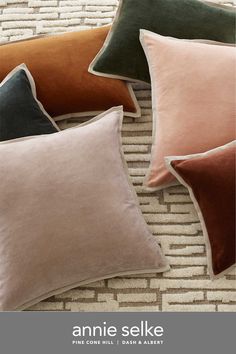 four different colored pillows sitting on top of a rug