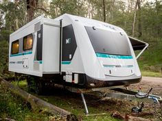 an rv parked on the side of a road in the woods next to a tree