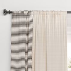 two curtains hanging on the side of a window with white and black striped drapes