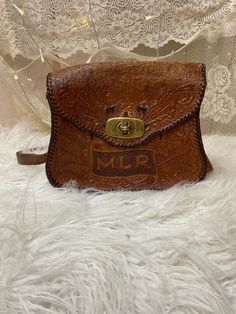 "Beautiful and well worn tooled leather bag, had lots of wear but is still in good usable condition! The top fold on the flap is a bit cracked. The initials MLR are tooled on the bag Bag measures 7\"x 9\" with a 42\" strap" Vintage Embossed Satchel For Everyday Use, Everyday Use Crossbody Shoulder Bag With Engraved Logo, Everyday Crossbody Shoulder Bag With Engraved Logo, Vintage Leather Shoulder Bag With Embossed Details, Vintage Leather Embossed Shoulder Bag, Vintage Embossed Leather Shoulder Bag, Vintage Embossed Satchel Bag, Vintage Brown Embossed Shoulder Bag, Vintage Brown Embossed Satchel