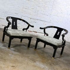 two black and white chairs sitting next to each other in front of a brick wall