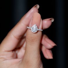 a woman's hand holding an engagement ring with a diamond on the top and side