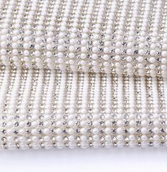 white beaded fabric with silver sequins and pearls on the side, close up