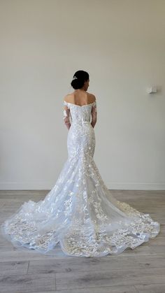 a woman in a white wedding dress is standing on the floor looking at her back