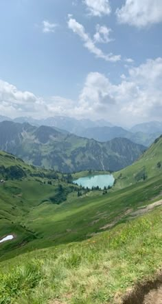 a man riding a bike on top of a lush green hillside next to a lake