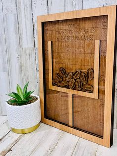 a wooden frame with some type of artwork on the wall next to a potted plant