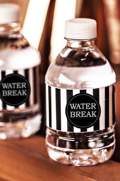 two water bottles with labels on them sitting on a wooden table next to each other