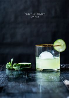 a cucumber and ice in a glass on a table next to a slice of cucumber