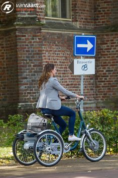 a woman riding a bike next to a street sign with an arrow pointing in opposite directions