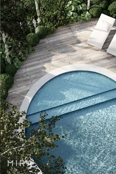 an aerial view of a swimming pool with lounge chairs on the deck and trees surrounding it