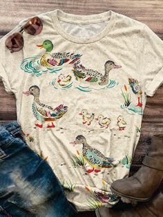 a t - shirt with ducks on it next to some jeans and boots, sunglasses