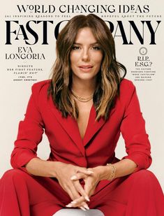 a woman in a red suit sitting on top of a white chair with her legs crossed