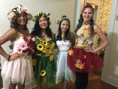 four girls dressed up in flower dresses posing for the camera with flowers on their heads