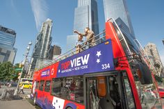 a red and blue double decker bus driving past tall buildings