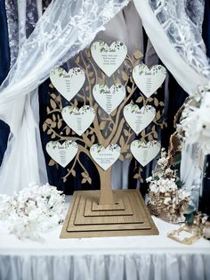 a wooden tree with hearts on it sitting in front of a white table cloth covered backdrop