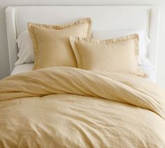 an unmade bed with yellow linens and pillows