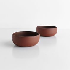 two brown bowls sitting on top of a white table