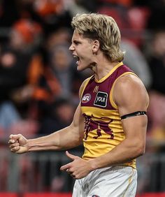 a male afl player with his mouth open and hands in the air, looking to his left