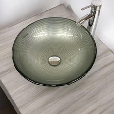 a green glass bowl sink sitting on top of a wooden counter next to a faucet