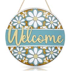 a welcome sign hanging from a rope with flowers on the front and blue, yellow and white background