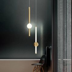 two lights hanging from the side of a wall next to a black chair and table